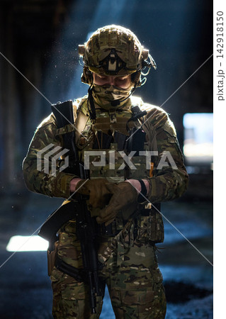 Soldier In Camouflage Tactical Gear With Rifle Standing In Dim Urban Light 142918150