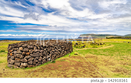 An ancient Rapa Nui stone wall stands in a grassy field at the Vaihu archaeological site on Easter Island, Chile 142918161