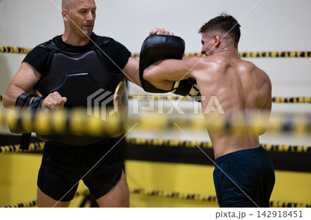 Boxer Training With Coach Doing Pad Work In Ring During Intense Boxing Workout Session Boxer Training With Coach Doing Pad Work In Ring During Intense Boxing Workout Session 142918451