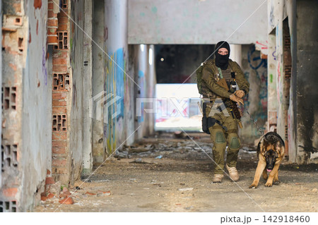 Armed Soldier With Military Dog On Urban Patrol Through Abandoned Building During Tactical Training 142918460