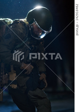 Tactical Soldier In Riot Gear With Helmet And Visor Preparing Equipment During Night Operation Tactical Soldier In Riot Gear With Helmet And Visor Preparing Equipment During Night Operation 142918462