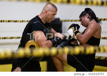 Female Boxer Training With Coach In Ring During Intense Pad Work Session For Fitness Female Boxer Training With Coach In Ring During Intense Pad Work Session For Fitness 142918757