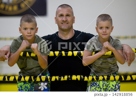 Father With Two Young Boys in Boxing Ring Coaching Youth Fighters and Family Training Session Father With Two Young Boys in Boxing Ring Coaching Youth Fighters and Family Training Session 142918856