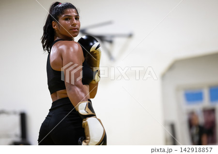 Female Boxer Athlete Training in Gym With Boxing Gloves and Intense Focus 142918857