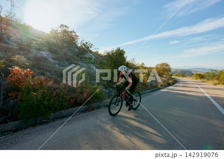 Female Cyclist Training on Scenic Road Through Hills at Sunrise Outdoor Cycling and Fitness Lifestyle 142919076