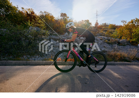 Female Cyclist Training On Road Bike During Autumn Ride Through Rocky Countryside 142919086