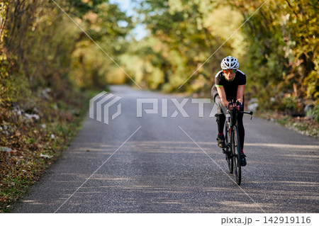 Solo Road Cyclist Training On Quiet Tree-Lined Country Road During Autumn Morning Ride Solo Road Cyclist Training On Quiet Tree-Lined Country Road During Autumn Morning Ride 142919116