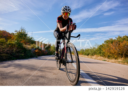 Female Cyclist Training On Road Bike During Sunny Autumn Ride Through Countryside Hills Female Cyclist Training On Road Bike During Sunny Autumn Ride Through Countryside Hills 142919126