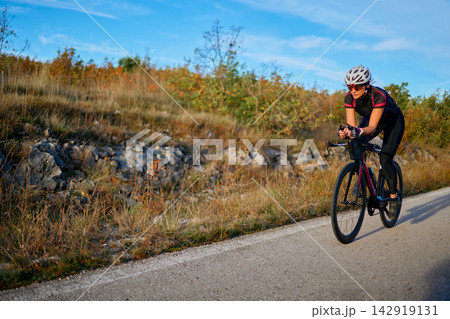 Female Cyclist Training on a Rural Road at Sunset Road Cycling Fitness and Endurance Female Cyclist Training on a Rural Road at Sunset Road Cycling Fitness and Endurance 142919131