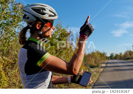 Female Cyclist Checking Phone While Pointing On Rural Road During Sunny Outdoor Training Ride Female Cyclist Checking Phone While Pointing On Rural Road During Sunny Outdoor Training Ride 142919167