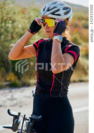 Female Cyclist Adjusting Sunglasses Before Ride Outdoors With Helmet And Road Bike Female Cyclist Adjusting Sunglasses Before Ride Outdoors With Helmet And Road Bike 142919300