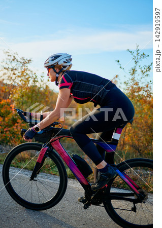 Female Cyclist Training on a Road Bike Outdoors During Autumn Sunrise Fitness Ride Female Cyclist Training on a Road Bike Outdoors During Autumn Sunrise Fitness Ride 142919597