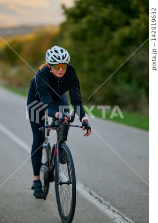 Female Cyclist Training on Road Bike During Outdoor Fitness Ride With Helmet and Sunglasses Female Cyclist Training on Road Bike During Outdoor Fitness Ride With Helmet and Sunglasses 142919632