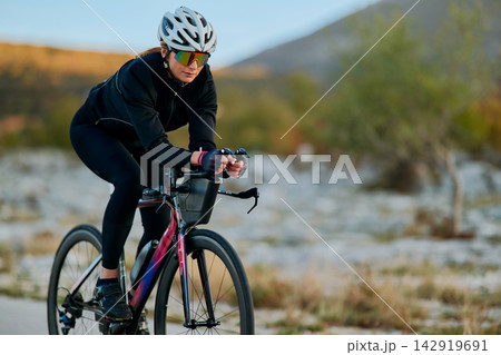 Female Cyclist Riding Road Bike in Cycling Gear on Scenic Outdoor Training Ride at Sunrise Female Cyclist Riding Road Bike in Cycling Gear on Scenic Outdoor Training Ride at Sunrise 142919691