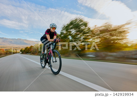 Female Cyclist Road Training At Speed Through Countryside On Racing Bike With Aerodynamic Gear 142919934