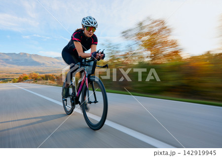 Female Cyclist Road Cycling at Speed on Open Road With Autumn Landscape and Mountains Female Cyclist Road Cycling at Speed on Open Road With Autumn Landscape and Mountains 142919945