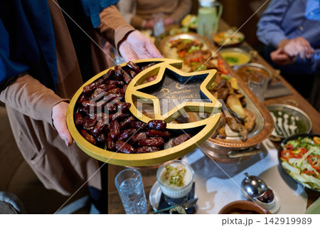 Muslim Woman Serving Dates On Crescent And Star Platter For Ramadan Iftar Dinner With Family Muslim Woman Serving Dates On Crescent And Star Platter For Ramadan Iftar Dinner With Family 142919989