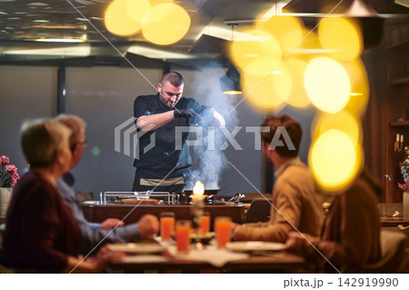 Chef Tableside Cooking for Family Dinner in Cozy Restaurant With Flames and Dramatic Presentation Chef Tableside Cooking for Family Dinner in Cozy Restaurant With Flames and Dramatic Presentation 142919990
