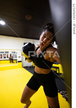 Female Boxer Training in Gym Hitting Heavy Bag During Intense Fitness Workout Session Female Boxer Training in Gym Hitting Heavy Bag During Intense Fitness Workout Session 142920175