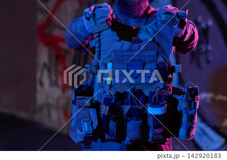Tactical Plate Carrier Vest With Pouches and Gear Held by Operator in Urban Night Lighting 142920183