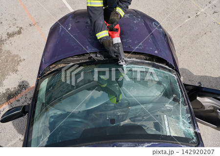 Firefighter Using Rescue Tool To Cut Windshield During Vehicle Extrication After Car Accident Firefighter Using Rescue Tool To Cut Windshield During Vehicle Extrication After Car Accident 142920207