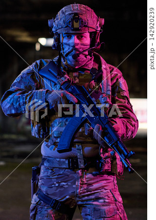 Armed Soldier in Tactical Gear Holding Assault Rifle in Night Urban Military Operation Armed Soldier in Tactical Gear Holding Assault Rifle in Night Urban Military Operation 142920239