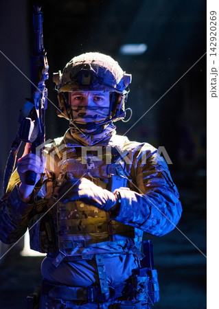 Serious Soldier in Tactical Gear Holding Rifle During Urban Nighttime Military Operation Serious Soldier in Tactical Gear Holding Rifle During Urban Nighttime Military Operation 142920269