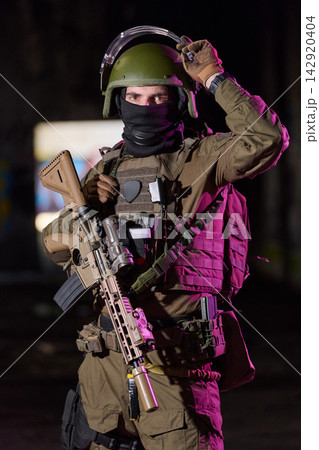 Armed Soldier in Tactical Gear With Rifle and Helmet During Nighttime Urban Operation 142920404