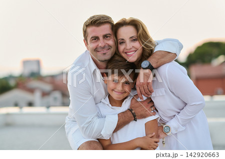 Smiling Parents Hugging Son On Rooftop Balcony Terrace With Sea View Happy Family Portrait Smiling Parents Hugging Son On Rooftop Balcony Terrace With Sea View Happy Family Portrait 142920663