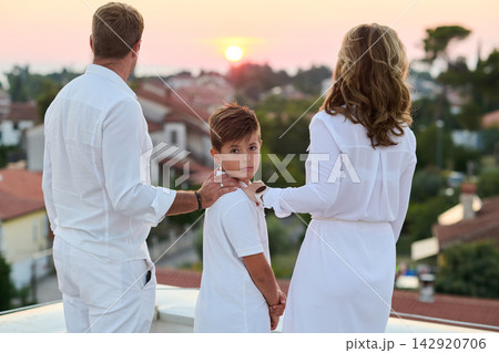 Family on Balcony at Sunset Overlooking Town and Sea Parents and Child on Rooftop Terrace Family on Balcony at Sunset Overlooking Town and Sea Parents and Child on Rooftop Terrace 142920706