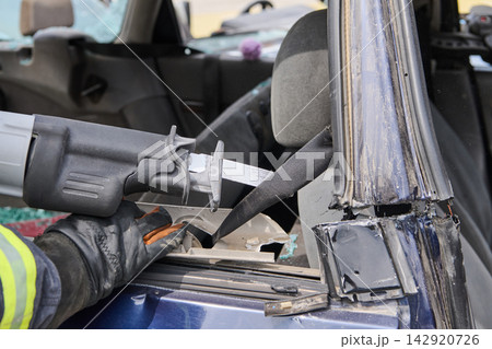Firefighter Using Reciprocating Saw For Vehicle Extrication Cutting Seatbelt During Car Rescue Operation Firefighter Using Reciprocating Saw For Vehicle Extrication Cutting Seatbelt During Car Rescue Operation 142920726