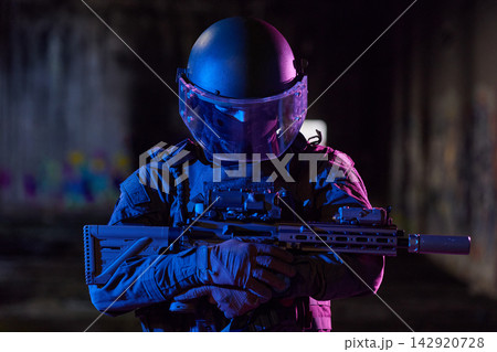 Tactical Officer in Ballistic Helmet and Visor Holding Rifle in Low-Light Urban Environment Tactical Officer in Ballistic Helmet and Visor Holding Rifle in Low-Light Urban Environment 142920728
