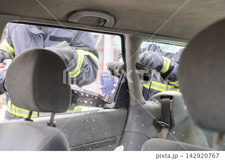 Firefighters Using Hydraulic Rescue Tool to Break Car Window During Emergency Vehicle Extrication Training Firefighters Using Hydraulic Rescue Tool to Break Car Window During Emergency Vehicle Extrication Training 142920767