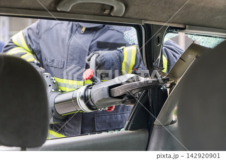Firefighter Using Hydraulic Rescue Tool To Extricate Passenger From Crashed Car With Broken Glass Firefighter Using Hydraulic Rescue Tool To Extricate Passenger From Crashed Car With Broken Glass 142920901