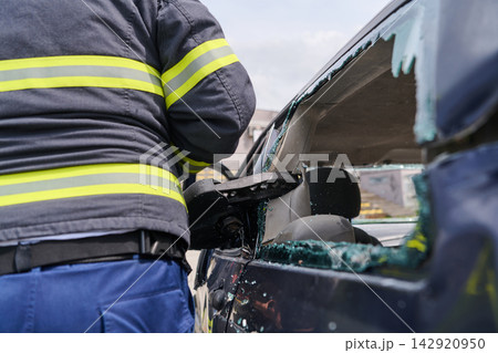 Firefighter Rescue Operation Breaking Car Window During Vehicle Extrication At Accident Scene Firefighter Rescue Operation Breaking Car Window During Vehicle Extrication At Accident Scene 142920950