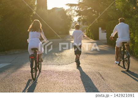 Family Cycling and Scootering Together at Sunset on a Quiet Residential Street 142921091