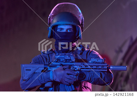 Tactical Officer In Helmet And Mask Holding Rifle In Low Light Urban Operation Scene 142921168