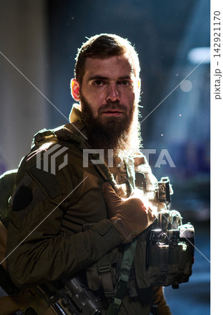 Tactical Soldier With Beard In Combat Gear Bathed In Dramatic Light Inside Urban Building 142921170