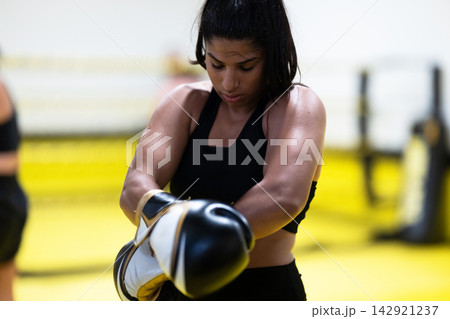 Focused Female Boxer Training With Gloves in Gym Ring Showing Strength, Determination and Fitness 142921237