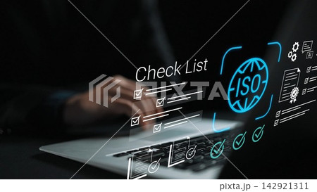 Hands typing on laptop with ISO checklist graphic overlay, representing quality management and standard compliance in modern business environment Gluon 142921311