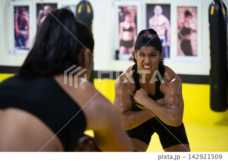 Determined Female Wrestler Training Intently in Gym Wrestling Practice on Yellow Mat Showing Strength Determined Female Wrestler Training Intently in Gym Wrestling Practice on Yellow Mat Showing Strength 142921509