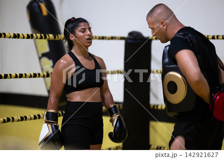 Female Boxer Training in Ring With Coach During Intense Boxing Workout Session Female Boxer Training in Ring With Coach During Intense Boxing Workout Session 142921627
