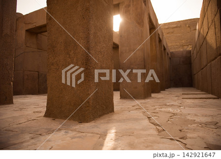 Low angle view of massive ancient temple stone columns with a dramatic light shaft piercing the ruins interior ideal for Egypt travel and archaeology Low angle view of massive ancient temple stone columns with a dramatic light shaft piercing the ruins interior ideal for Egypt travel and archaeology 142921647