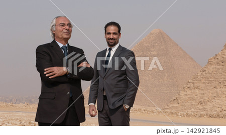Two multigenerational executives in power suits pose confidently before iconic Giza Pyramids representing MENA leadership and corporate ambition 142921845