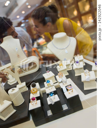 Couple browsing jewelry display in a store window with sparkling rings and necklaces on show Couple browsing jewelry display in a store window with sparkling rings and necklaces on show 142922046