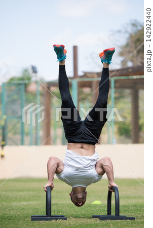 Middle Eastern Arab man performing handstand push-up in outdoor fitness park during CrossFit workout session Middle Eastern Arab man performing handstand push-up in outdoor fitness park during CrossFit workout session 142922440