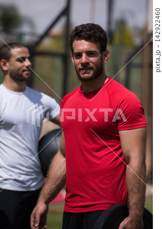 Middle Eastern man training at outdoor CrossFit gym with a friend during sunny workout session 142922460