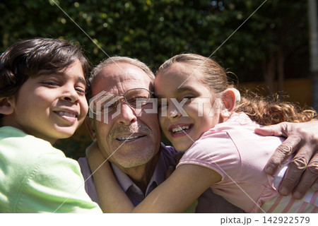 Middle Eastern Arab grandfather hugging grandchildren in backyard family portrait showing joy and affection Middle Eastern Arab grandfather hugging grandchildren in backyard family portrait showing joy and affection 142922579