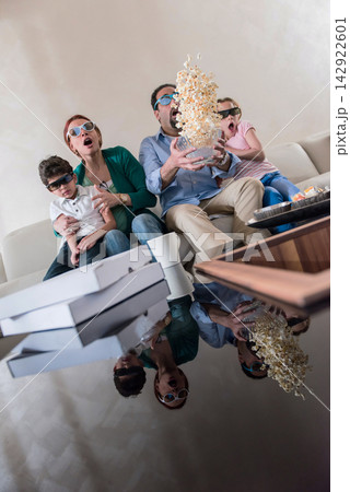 Modern Middle Eastern family watching movie together at home with popcorn flying in living room surprise Modern Middle Eastern family watching movie together at home with popcorn flying in living room surprise 142922601