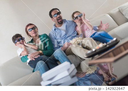 Modern Middle Eastern Arab family watching a movie together on the couch with popcorn and 3D glasses Modern Middle Eastern Arab family watching a movie together on the couch with popcorn and 3D glasses 142922647